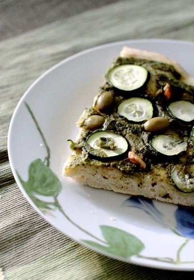 Green pizza with rocket and basil pesto with walnuts, olives and courgettes